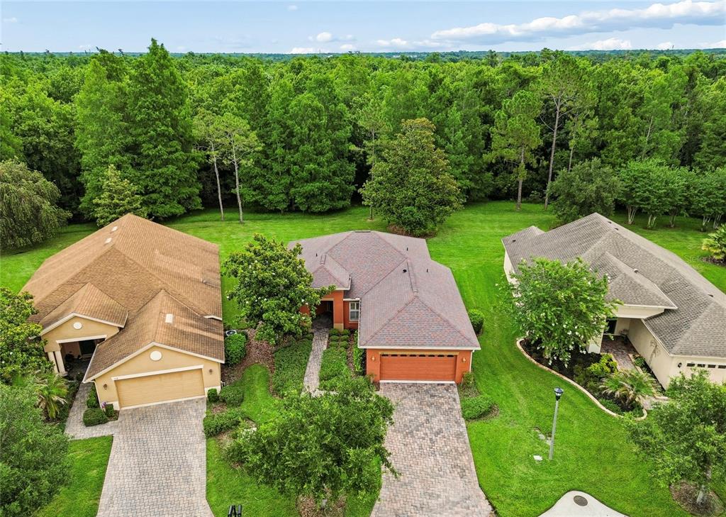 An aerial view shows three suburban houses with paved driveways and large, tree-lined backyards — 136 SORRENTO RD, POINCIANA, FL