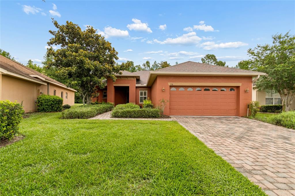 A single-story house with a terracotta-colored exterior, a two-car garage, and a paved driveway — 136 SORRENTO RD, POINCIANA, FL