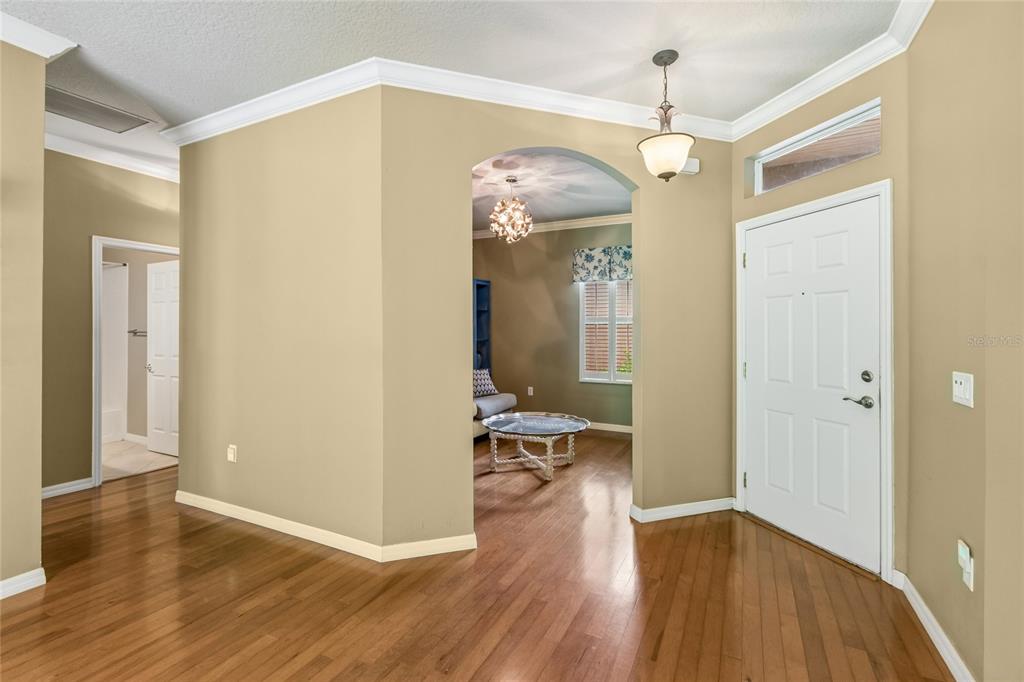 An entryway with hardwood floors, a white front door, and an arched opening to a room — 136 SORRENTO RD, POINCIANA, FL