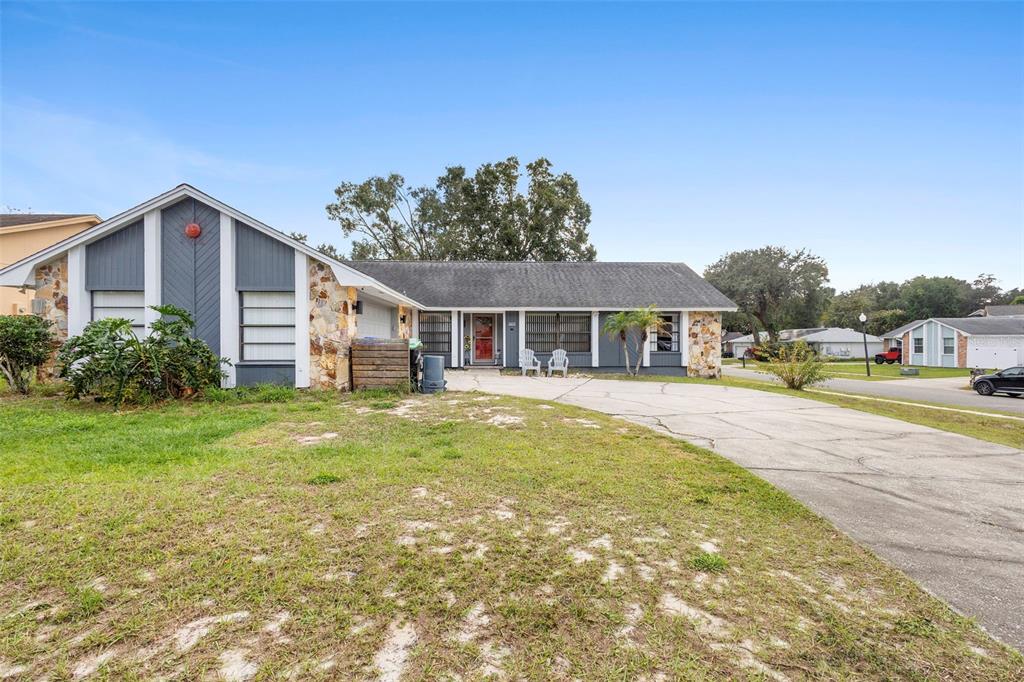 A single-story house with a stone facade, gray siding, and a concrete driveway — 8611 PARK HIGHLAND DRIVE, ORLANDO, FL