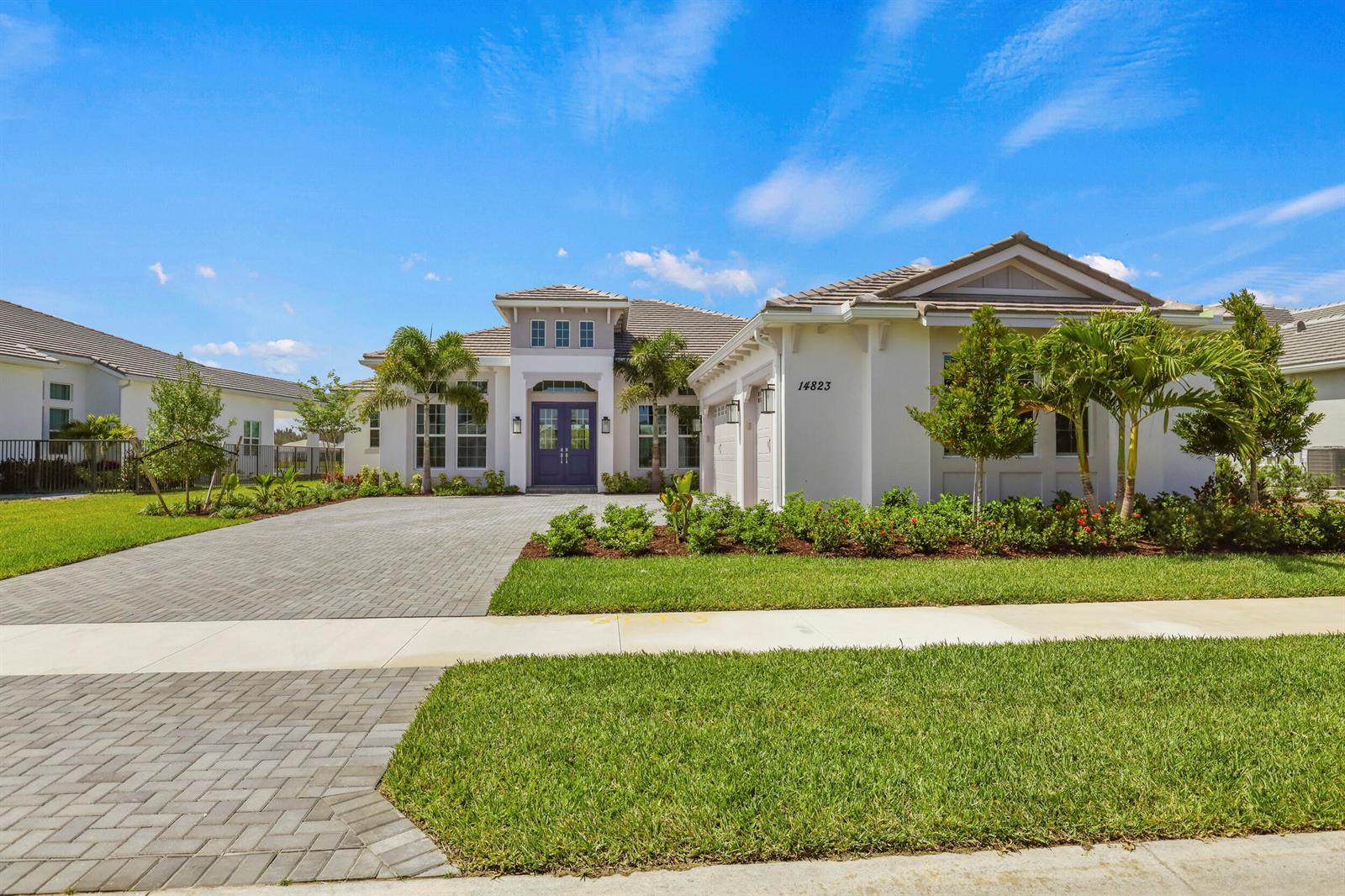 A single-story house with a paved driveway, purple front door, and landscaped front yard — 14823 Wildwood Circle, Westlake FL 33470, WESTLAKE, FL