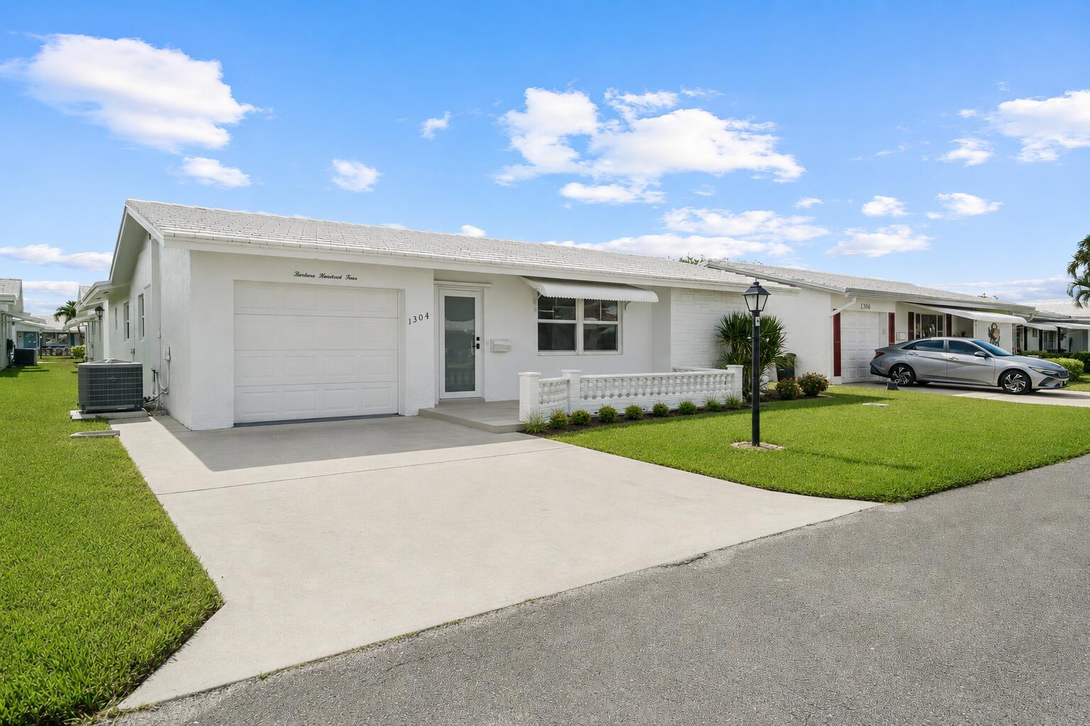 A white single-story house with a garage, concrete driveway, and a small front patio — 1304 SW 23rd Street, Boynton Beach FL 33426, BOYNTON BEACH, FL