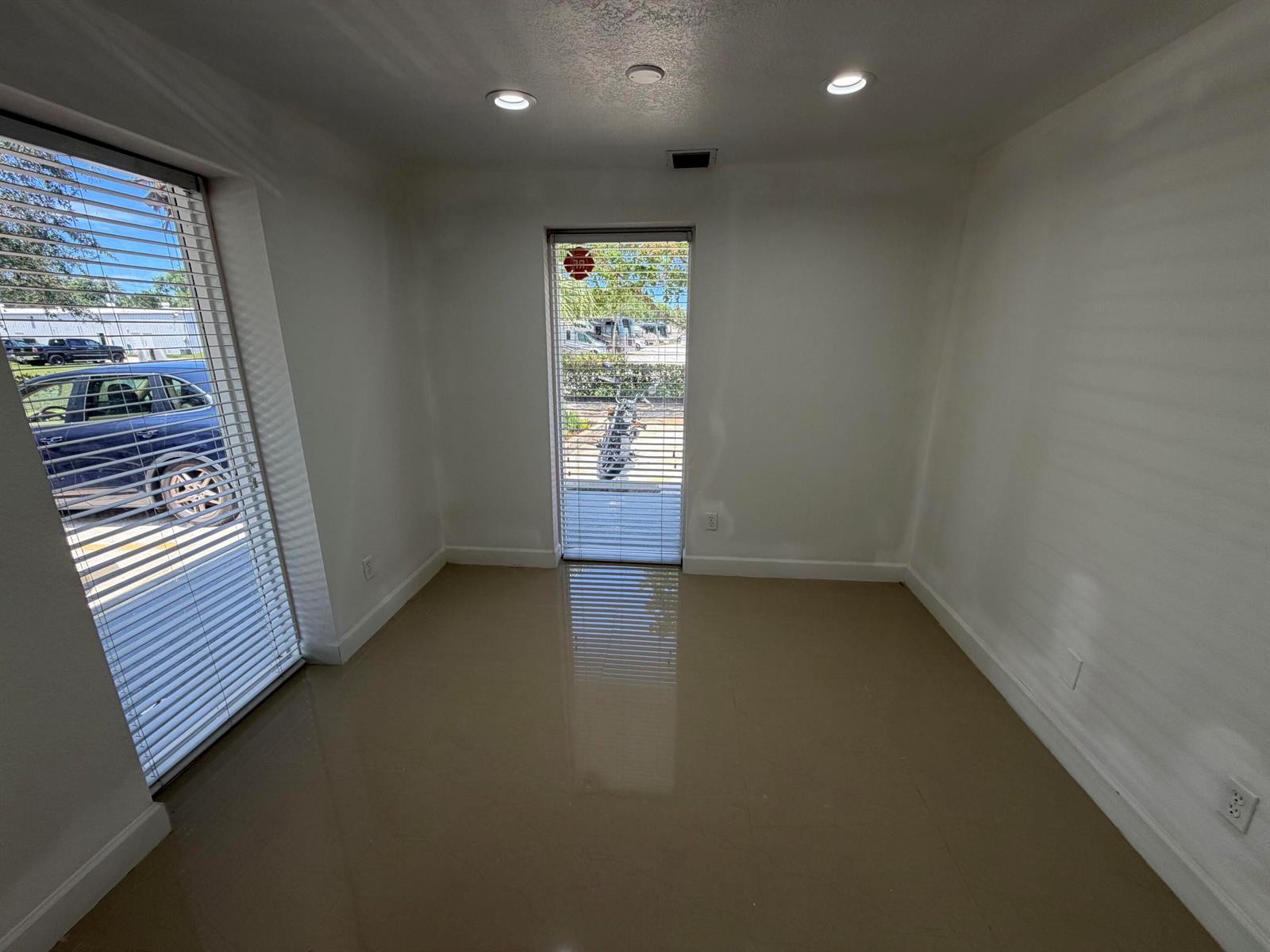 A small, empty room with light-colored tile flooring, white walls, and two windows with blinds — 500 Commerce Way Way W # 7, Jupiter FL 33458, JUPITER, FL