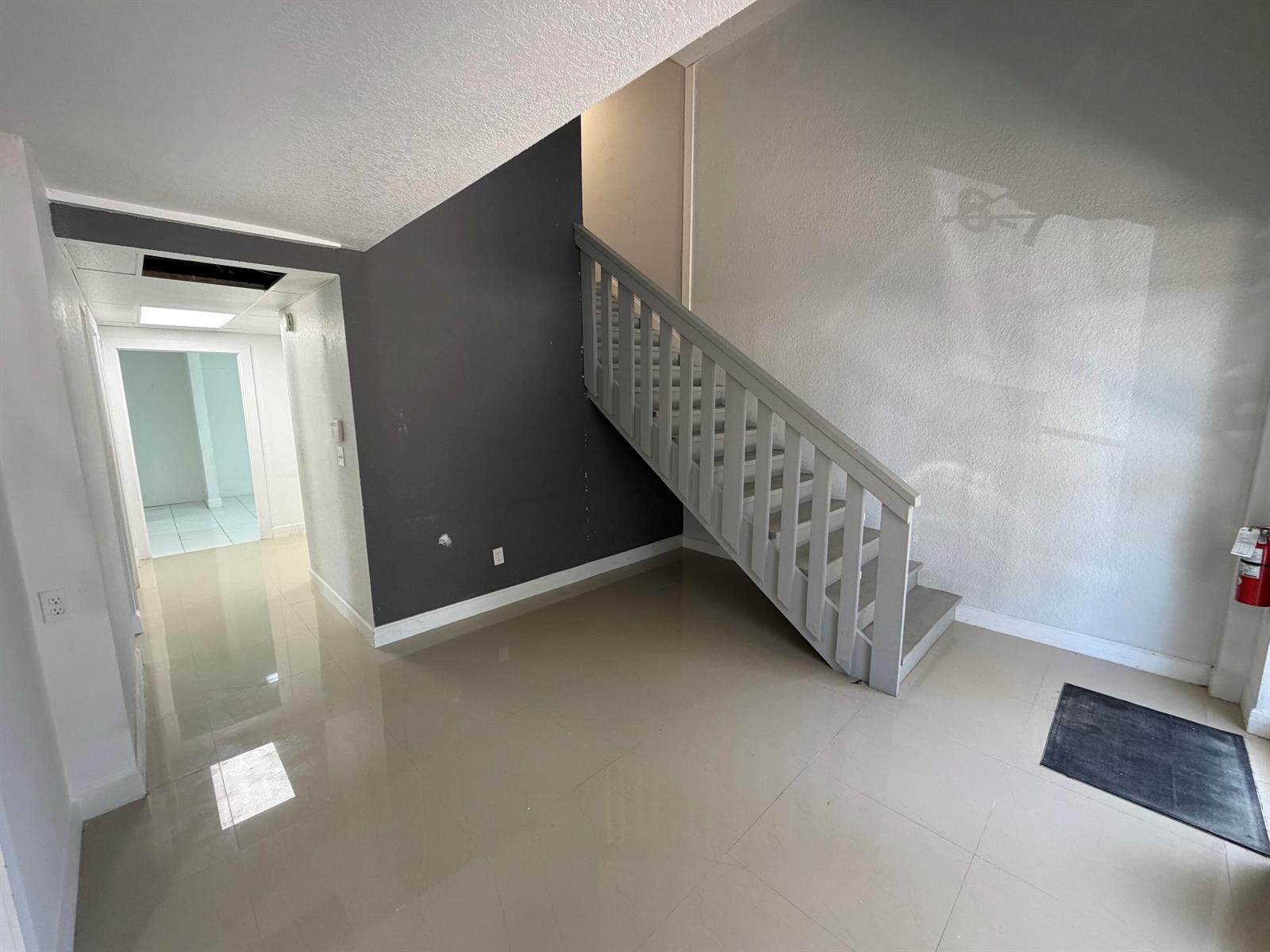 A hallway with light tile flooring features a glass-paneled door and a beach-themed wall art — 500 Commerce Way Way W # 7, Jupiter FL 33458, JUPITER, FL