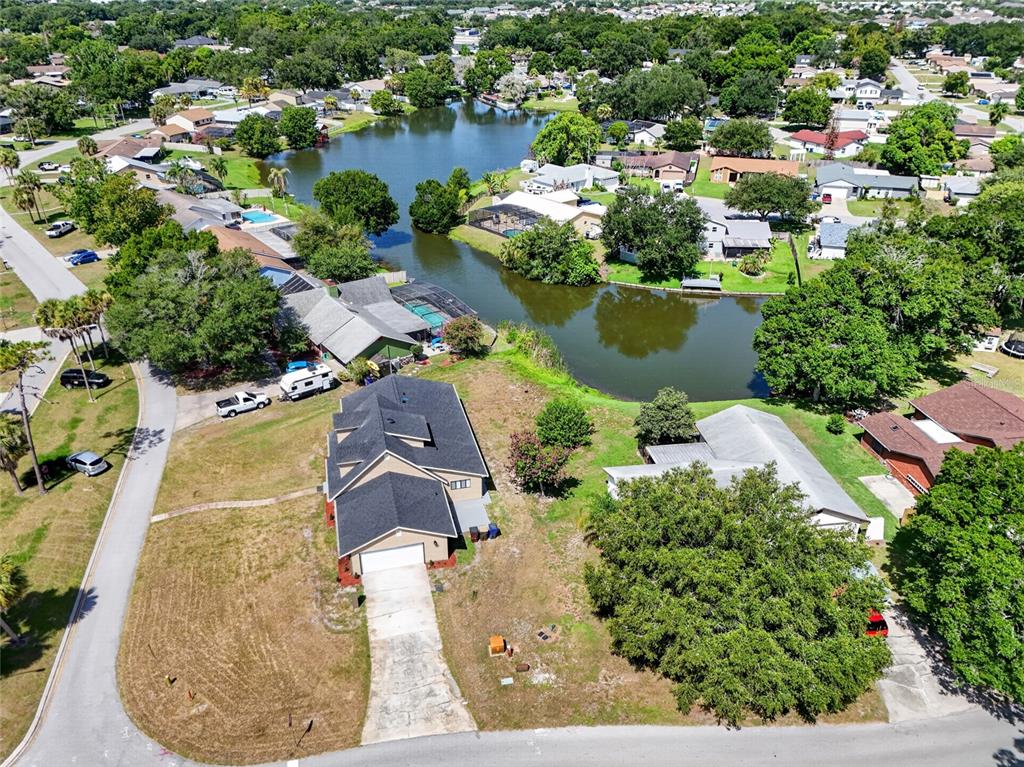 An aerial view shows a suburban house with a dark roof near a small lake — 4400 LAKE TRUDY DRIVE, ST CLOUD, FL