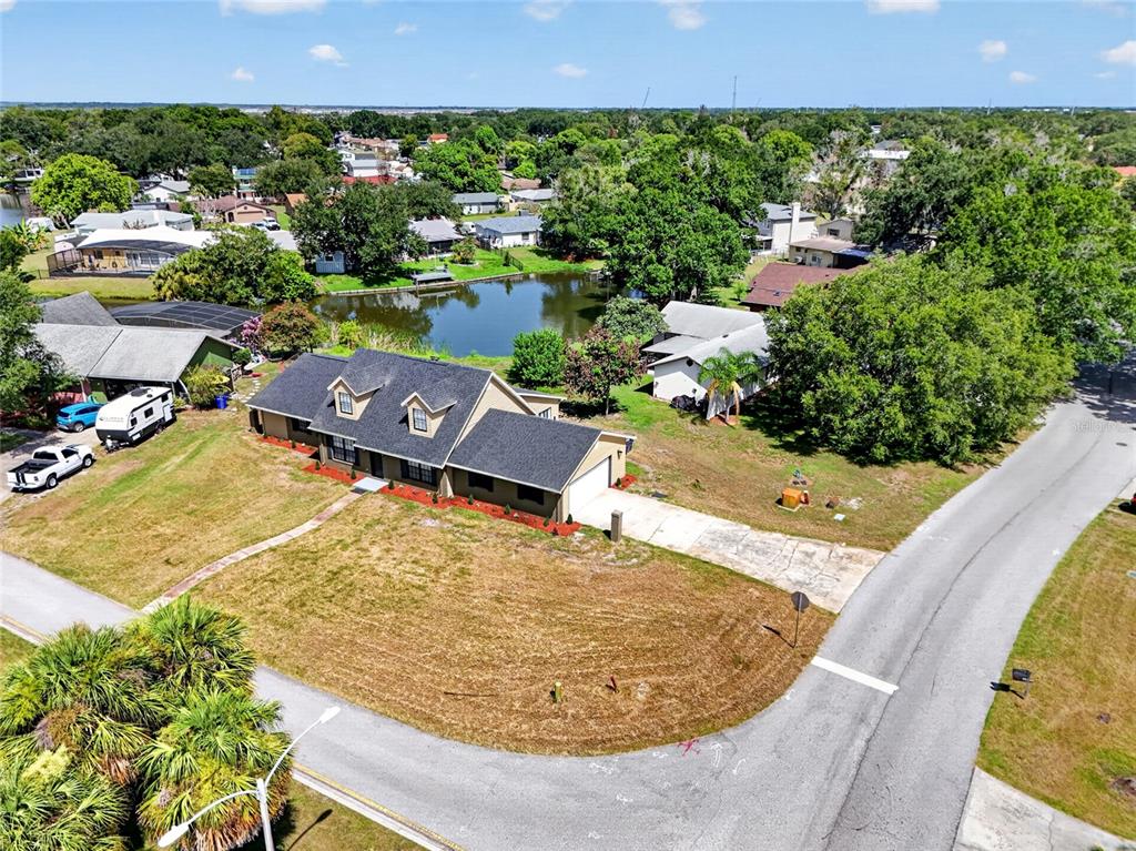 An aerial view shows a single-story house with a dark roof near a small pond — 4400 LAKE TRUDY DRIVE, ST CLOUD, FL