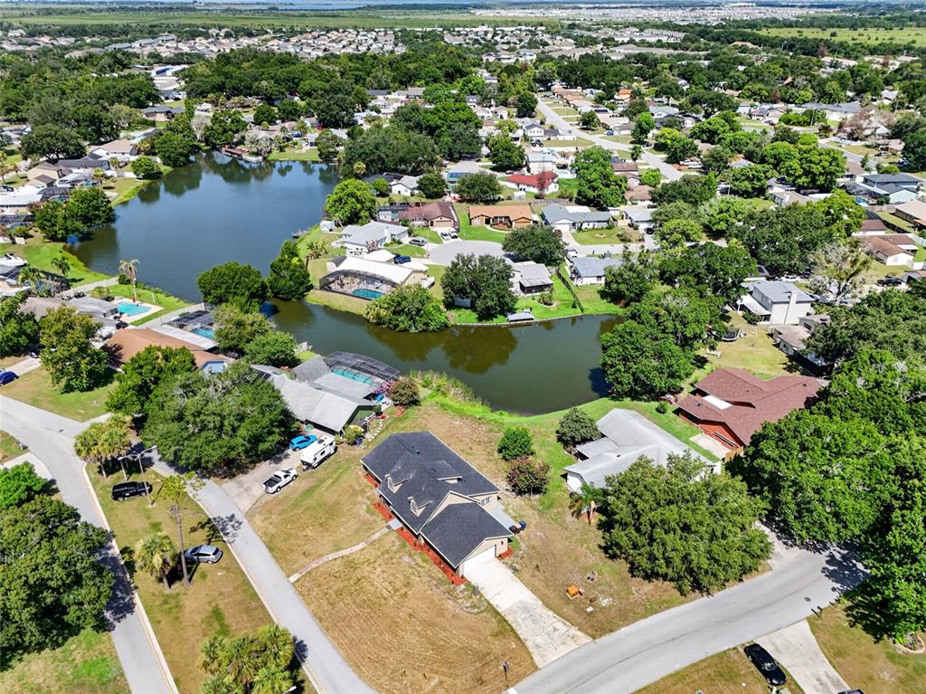 An aerial view shows a suburban neighborhood with houses surrounding a small lake — 4400 LAKE TRUDY DRIVE, ST CLOUD, FL