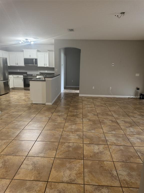 An open-concept kitchen with white cabinets and tile flooring flows into a living area — 3504 PORTVIEW COURT, KISSIMMEE, FL