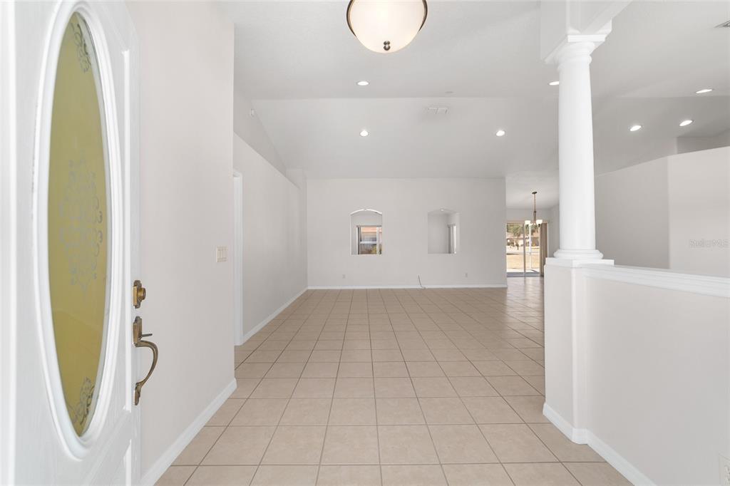 An entryway with tiled floors leads into a bright, open-concept living area with vaulted ceilings — 4560 NW 5TH COURT, OCALA, FL