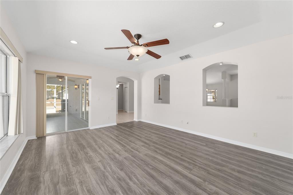 A living room with gray wood-look flooring, a ceiling fan, and two arched wall niches — 4560 NW 5TH COURT, OCALA, FL