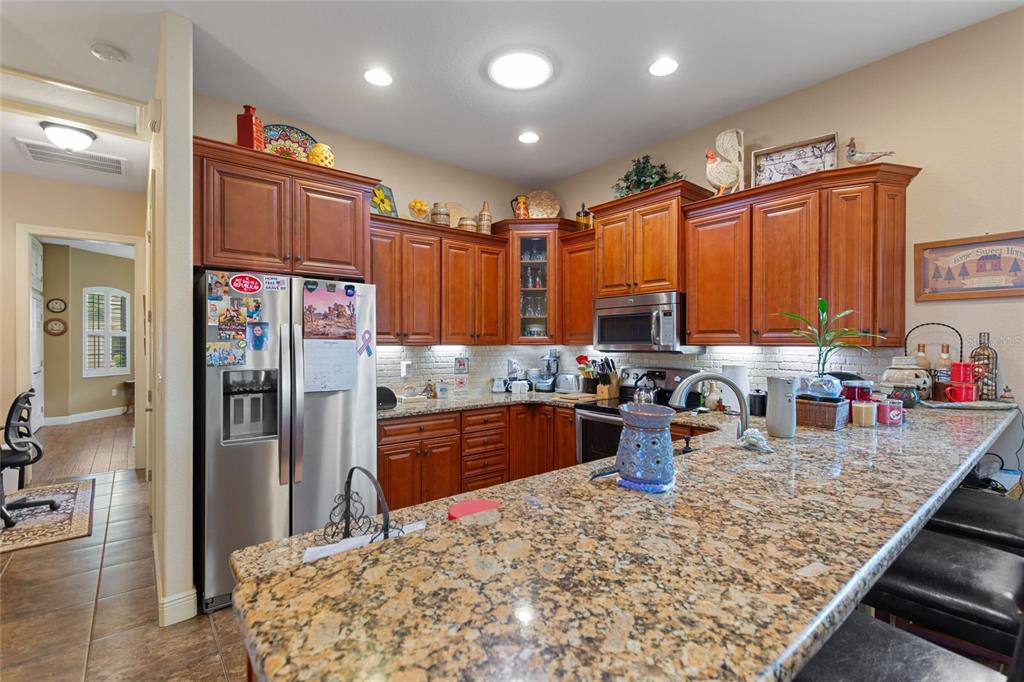 A kitchen features wood cabinets, granite countertops, stainless steel appliances, and a breakfast bar — 548 NARROW POND ROAD, POLK CITY, FL