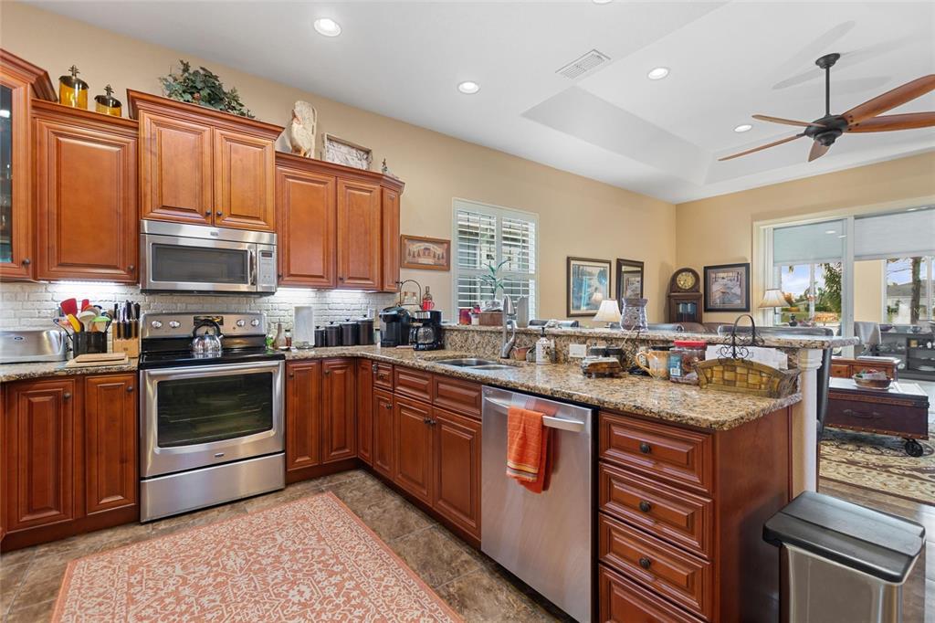 A kitchen features wood cabinets, granite countertops, stainless steel appliances, and a tile floor — 548 NARROW POND ROAD, POLK CITY, FL