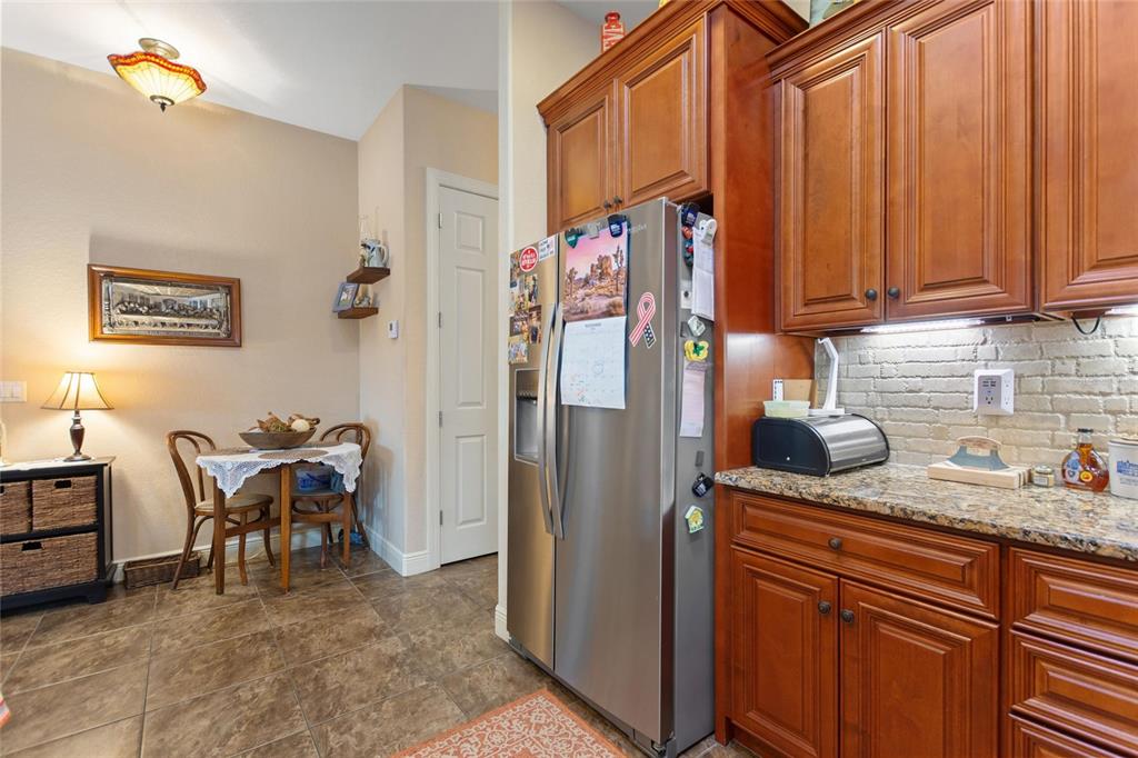 A kitchen features wood cabinets, granite countertops, a stainless steel refrigerator, and a small dining area — 548 NARROW POND ROAD, POLK CITY, FL