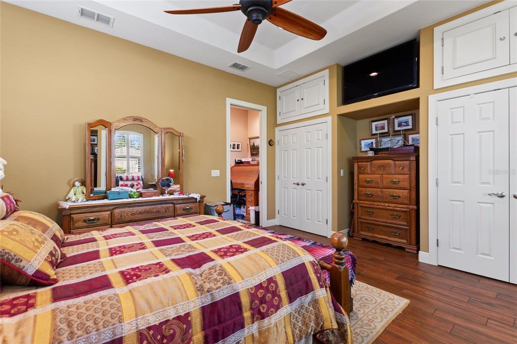 A bedroom features a patterned quilt on the bed, wooden furniture, and a ceiling fan — 548 NARROW POND ROAD, POLK CITY, FL