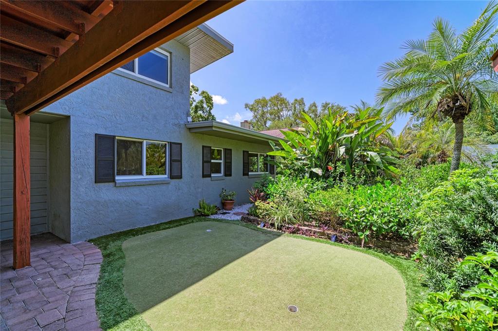 A backyard putting green sits next to a two-story house with a brick patio — 4509 S LOCKWOOD RIDGE ROAD, SARASOTA, FL