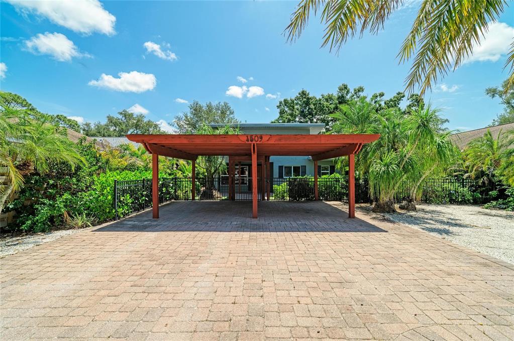 A red wooden carport stands over a paved driveway in front of a house — 4509 S LOCKWOOD RIDGE ROAD, SARASOTA, FL