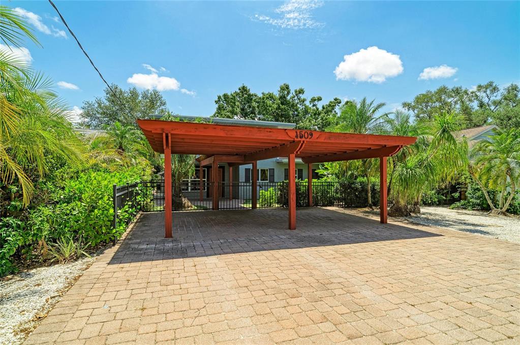 A paved driveway leads to a wooden carport structure in front of a house — 4509 S LOCKWOOD RIDGE ROAD, SARASOTA, FL