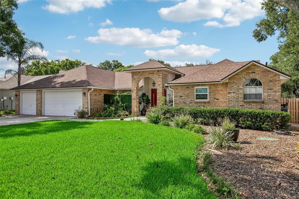 A single-story brick house with a two-car garage, arched entryway, and a large front lawn — 3949 APPLETREE DRIVE, VALRICO, FL