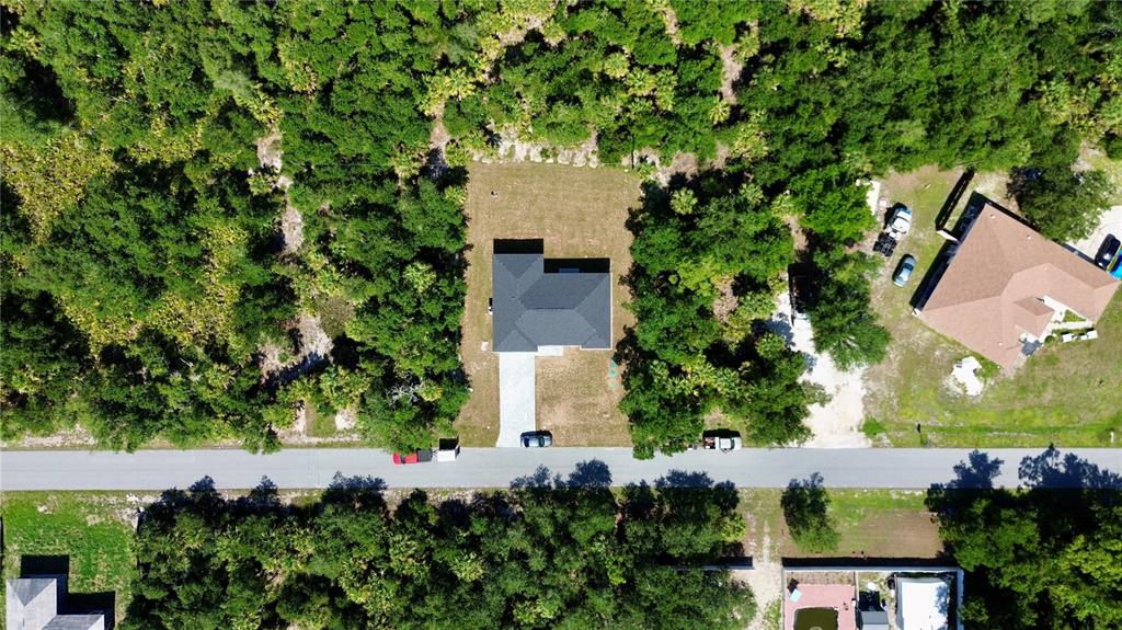 An aerial view shows a house with a dark roof centered on a wooded lot — 3297 AUDETTE STREET, PORT CHARLOTTE, FL