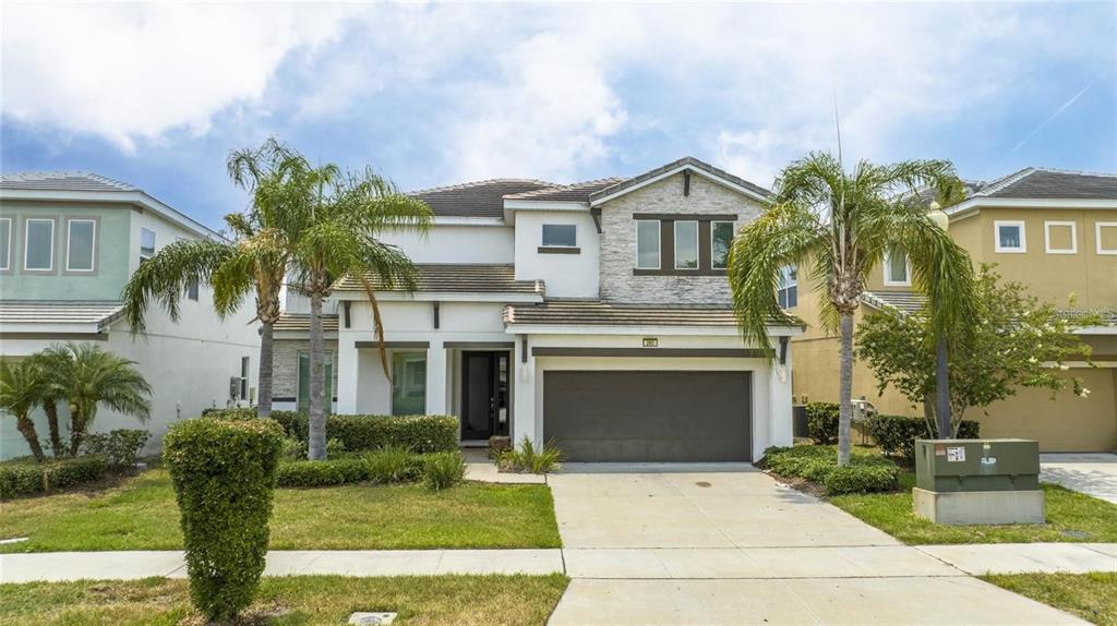 A two-story suburban house with a stone facade, a two-car garage, and two palm trees — 280 BALLO DRIVE, KISSIMMEE, FL