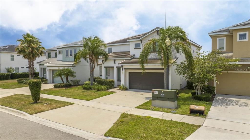 A two-story suburban house with a two-car garage, palm trees, and a concrete driveway — 280 BALLO DRIVE, KISSIMMEE, FL