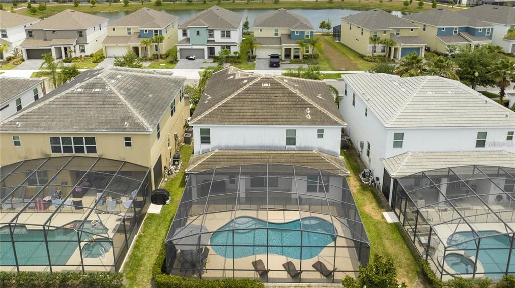 An aerial view shows three suburban houses with screened-in pools in their backyards — 280 BALLO DRIVE, KISSIMMEE, FL