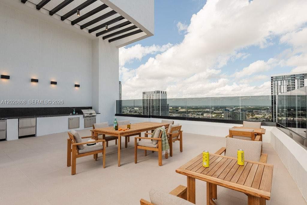 An outdoor rooftop terrace features a dining area, a built-in grill, and glass railings — 225 N Miami Ave # 2810, Miami FL 33128, MIAMI, FL