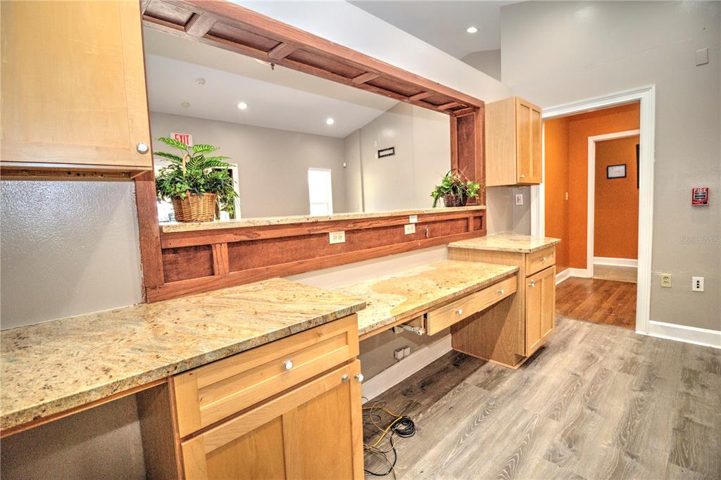 A kitchen or office area features light wood cabinets, granite countertops, and a large pass-through window — 2131 SW 22ND PLACE UNIT 100, OCALA, FL