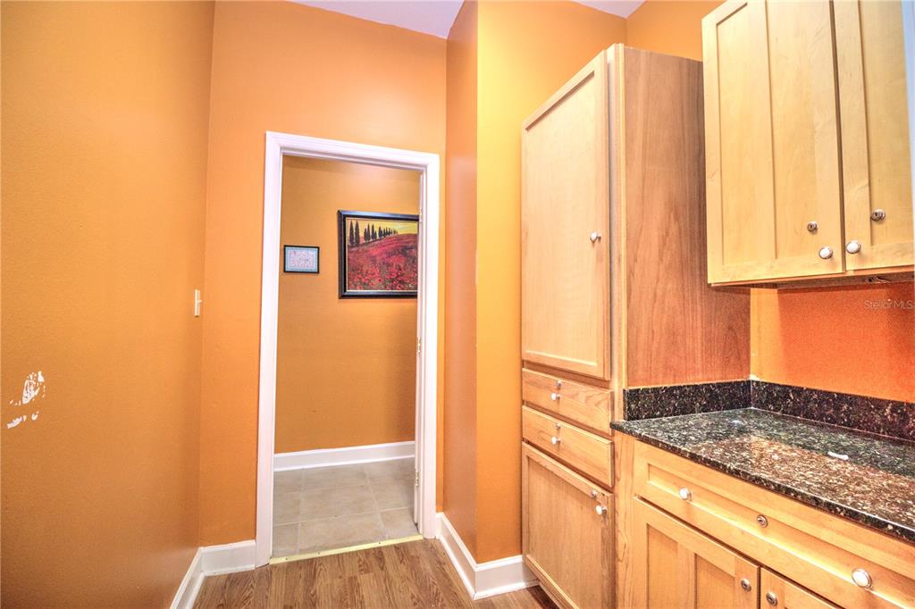 A laundry room features light wood cabinets, dark granite countertops, and orange walls — 2131 SW 22ND PLACE UNIT 100, OCALA, FL