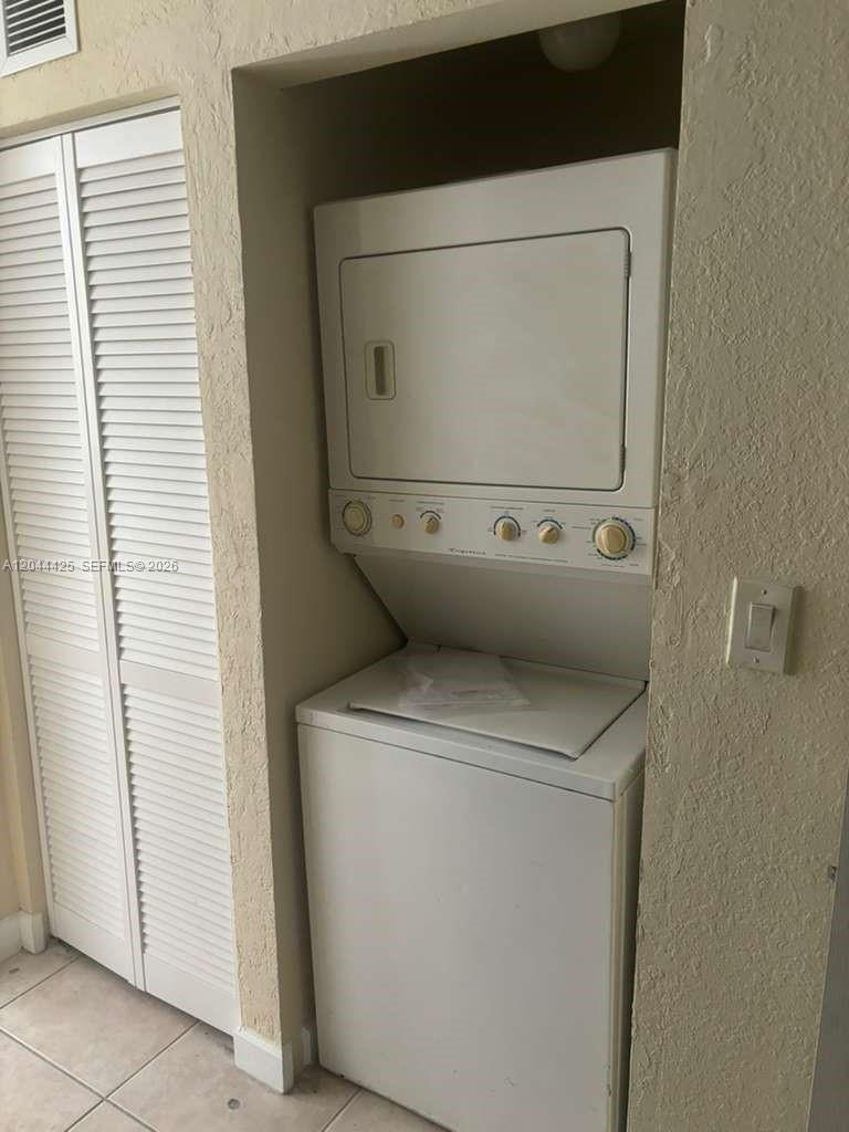 A white stacked washer and dryer unit is installed in a recessed laundry closet — 1663 SE 27th Dr # 207, Homestead FL 33035, HOMESTEAD, FL
