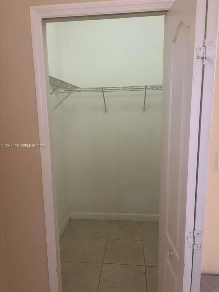 A walk-in closet features white wire shelving and light-colored tile flooring — 1663 SE 27th Dr # 207, Homestead FL 33035, HOMESTEAD, FL