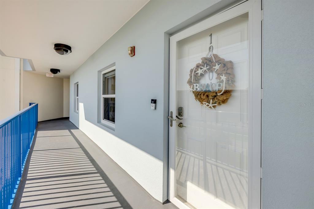 An exterior walkway leads to a white door with a beach-themed wreath — 5300 S ATLANTIC AVENUE UNIT 19-504, NEW SMYRNA BEACH, FL