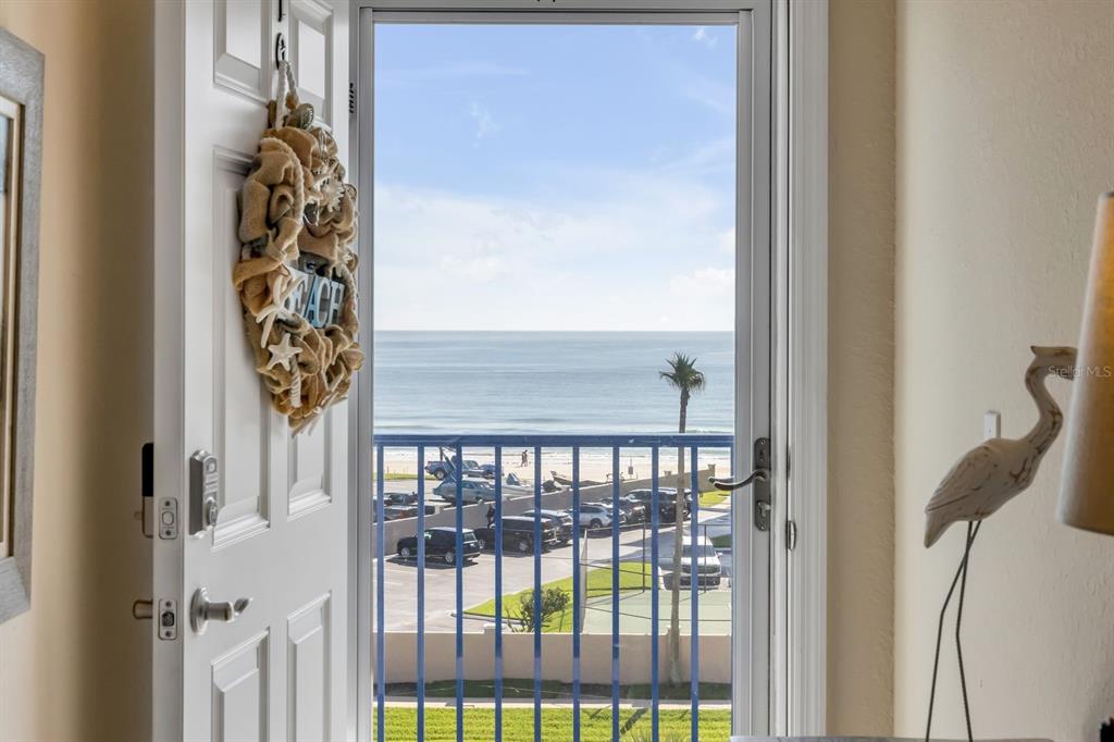 An open door reveals a view of a beach, parking lot, and ocean beyond — 5300 S ATLANTIC AVENUE UNIT 19-504, NEW SMYRNA BEACH, FL