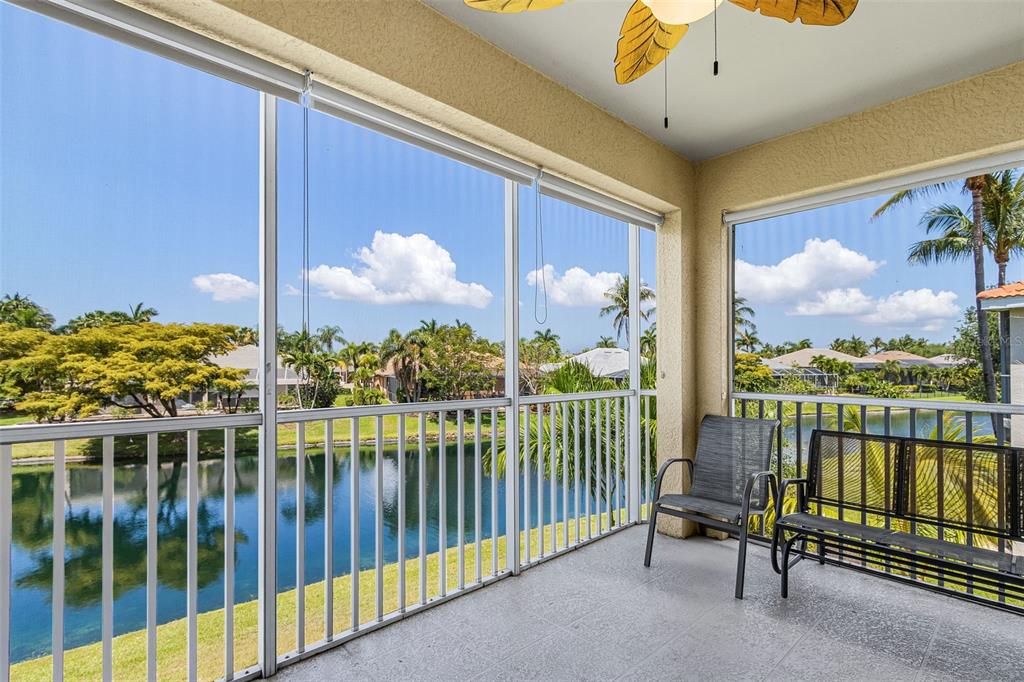 A screened-in balcony features a tiled floor, a ceiling fan, and views of a lake — 5626 CAPE HARBOUR DRIVE UNIT 202, CAPE CORAL, FL