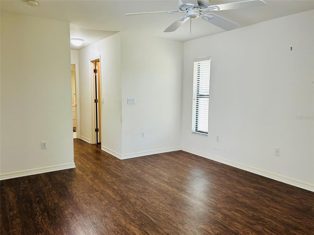 An empty room with wood-look flooring, a ceiling fan, and a window with blinds — 304 PINE GLEN COURT, ENGLEWOOD, FL