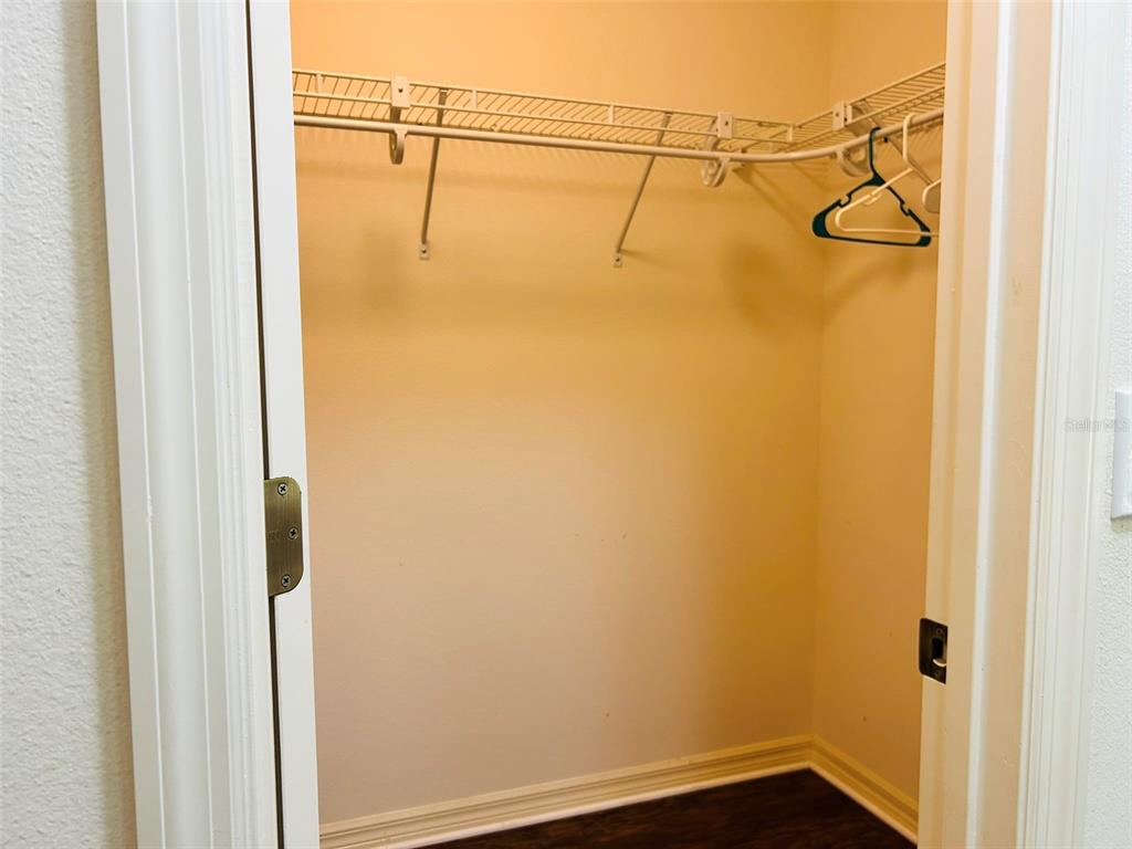 A walk-in closet features white wire shelving, beige walls, and dark wood-look flooring — 304 PINE GLEN COURT, ENGLEWOOD, FL