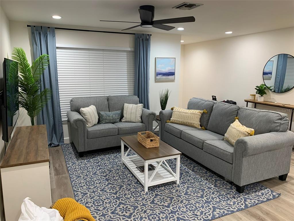 A living room features gray sofas, a patterned rug, and a wooden coffee table — 23184 GLORY AVENUE, PORT CHARLOTTE, FL