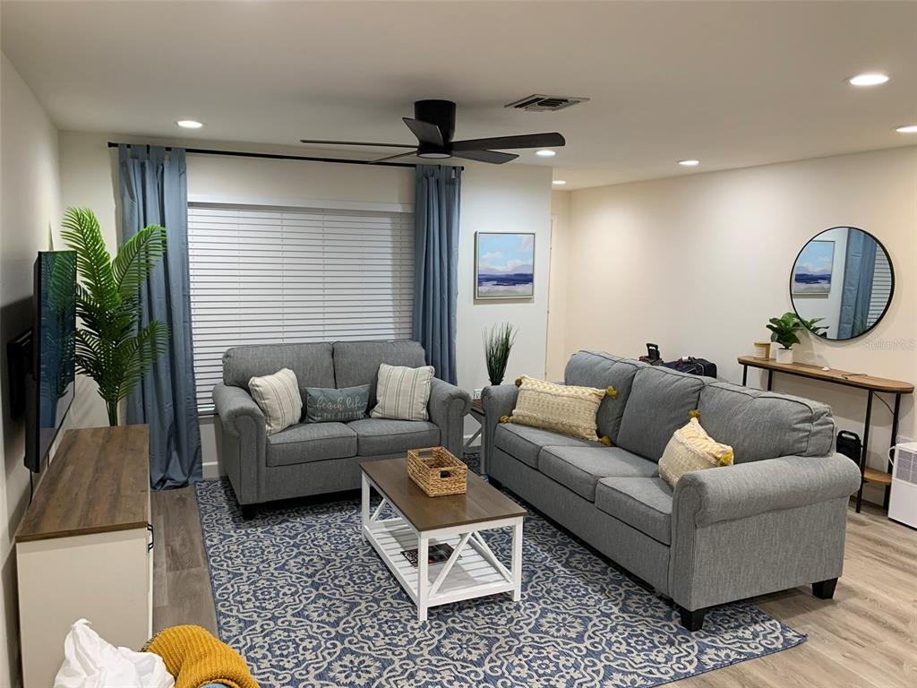 A living room features two gray sofas, a patterned rug, and a wooden coffee table — 23184 GLORY AVENUE, PORT CHARLOTTE, FL