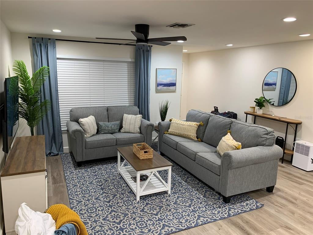 A living room features gray sofas, a patterned blue rug, and a wooden coffee table — 23184 GLORY AVENUE, PORT CHARLOTTE, FL