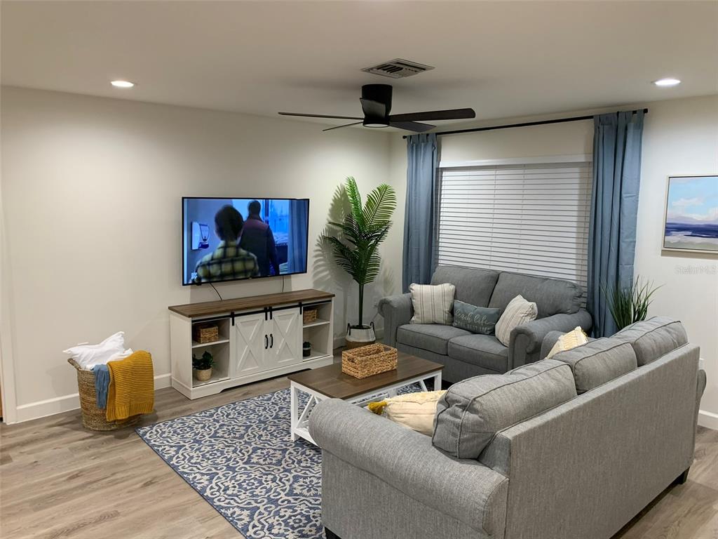 A living room features a grey sofa, a television on a console, and a patterned rug — 23184 GLORY AVENUE, PORT CHARLOTTE, FL