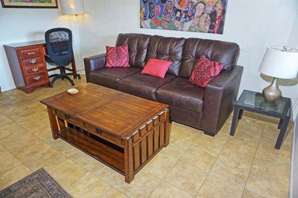 A living room features a brown leather sofa, a wooden coffee table, and a desk — 20853 HAULOVER COVE UNIT A12, LUTZ, FL
