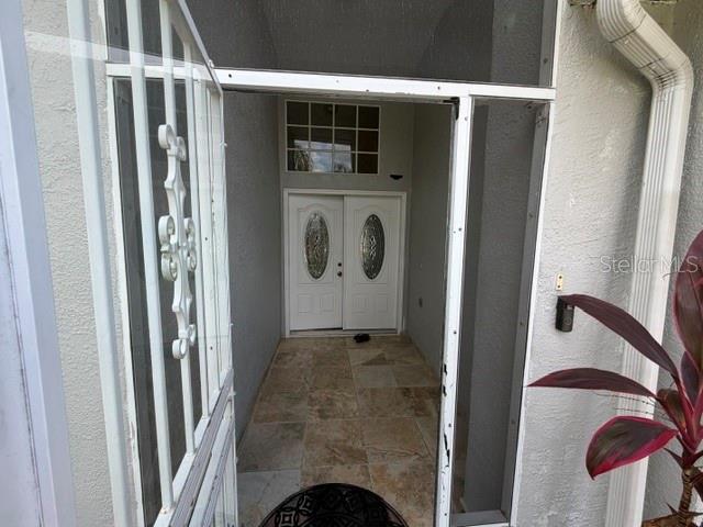 A white double front door is visible through a screen door on a tiled porch — 4049 SAVAGE STATION CIRCLE, NEW PORT RICHEY, FL