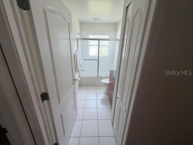 A view through a doorway into a bathroom with white tile floors and a shower — 4049 SAVAGE STATION CIRCLE, NEW PORT RICHEY, FL