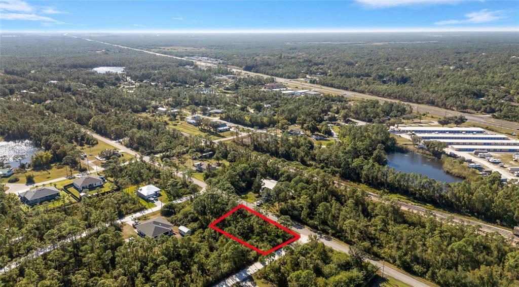 An aerial view shows a rectangular vacant lot outlined in red amidst a wooded area — 12198 BUENOS COURT, PUNTA GORDA, FL