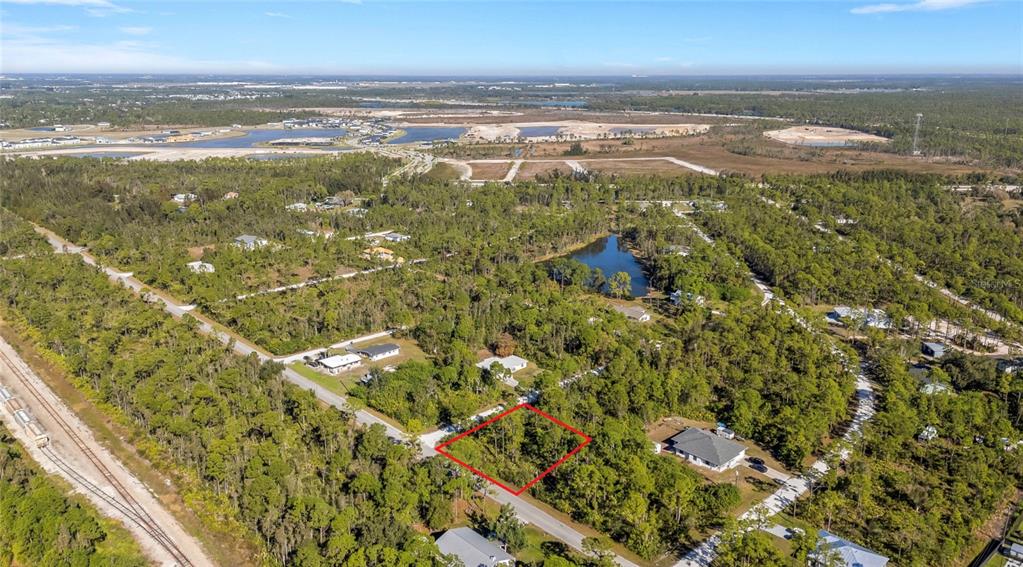 An aerial view shows a vacant, rectangular lot outlined in red within a wooded area — 12198 BUENOS COURT, PUNTA GORDA, FL