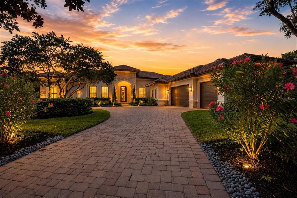 A paved driveway leads to the front entrance and garage of a single-story stucco house — 9261 MCDANIEL LANE, SARASOTA, FL