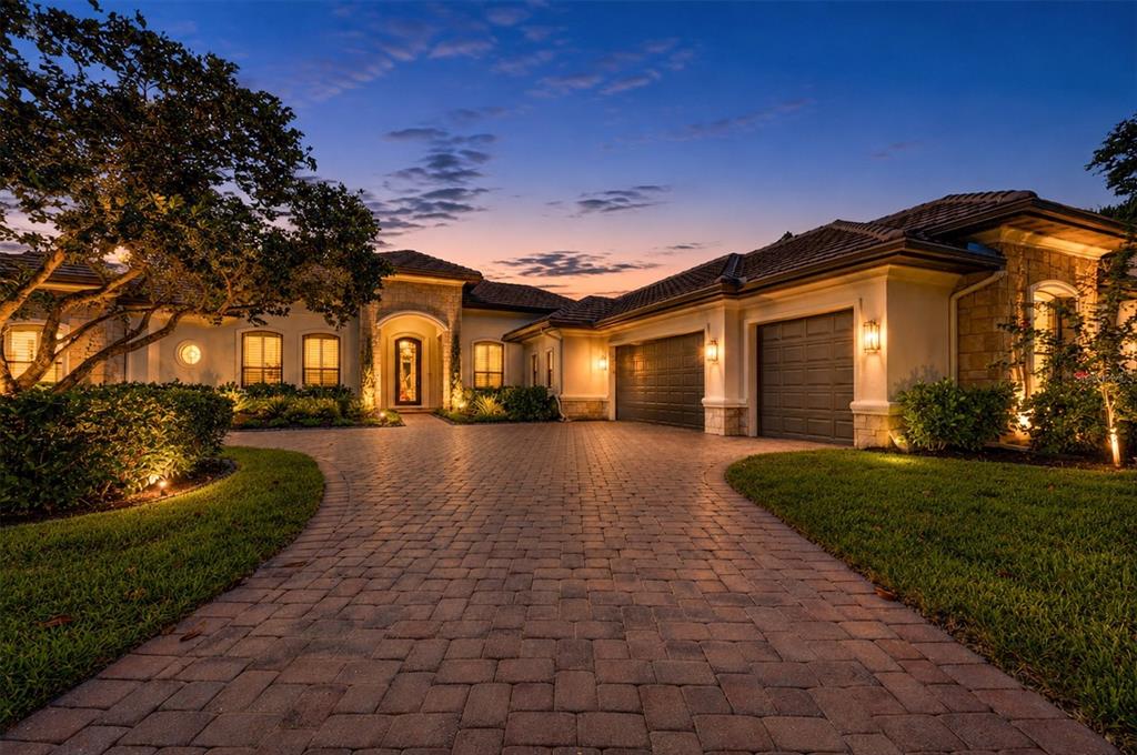 A paved driveway leads to the front entrance and two-car garage of a suburban home — 9261 MCDANIEL LANE, SARASOTA, FL