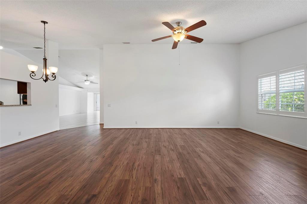A spacious, empty living room features dark wood-look flooring, white walls, and a ceiling fan — 5368 KELLY DRIVE UNIT 17, SARASOTA, FL