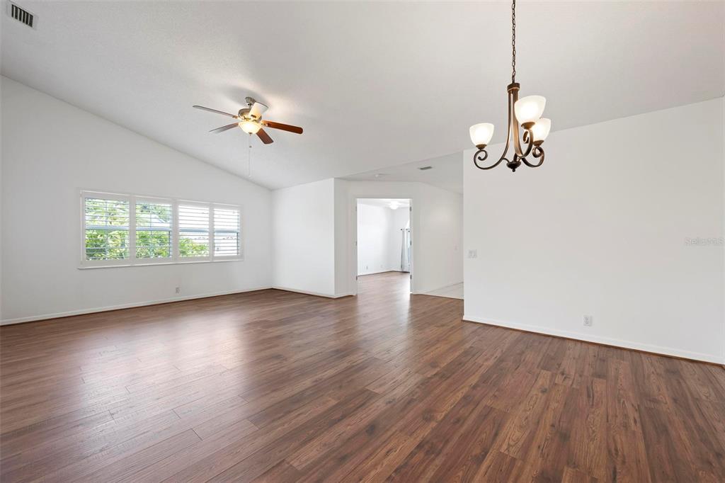 A spacious living room features white walls, wood-look flooring, a ceiling fan, and a chandelier — 5368 KELLY DRIVE UNIT 17, SARASOTA, FL