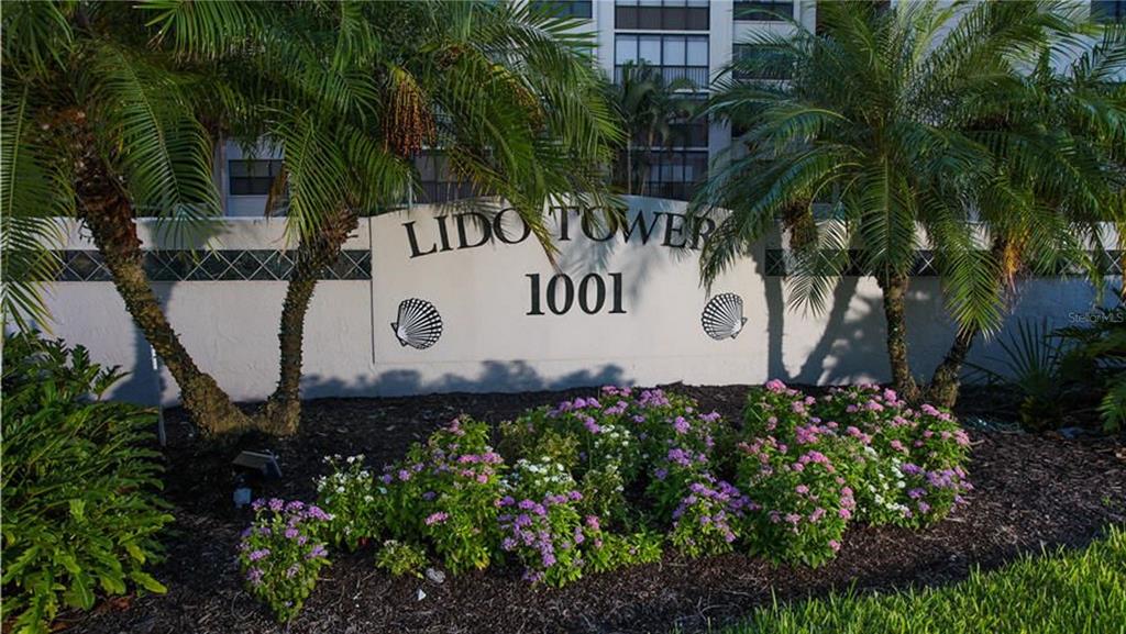 A sign for Lido Tower 1001 stands behind a garden of pink flowers and palm trees — 1001 BENJAMIN FRANKLIN DRIVE UNIT 506, SARASOTA, FL